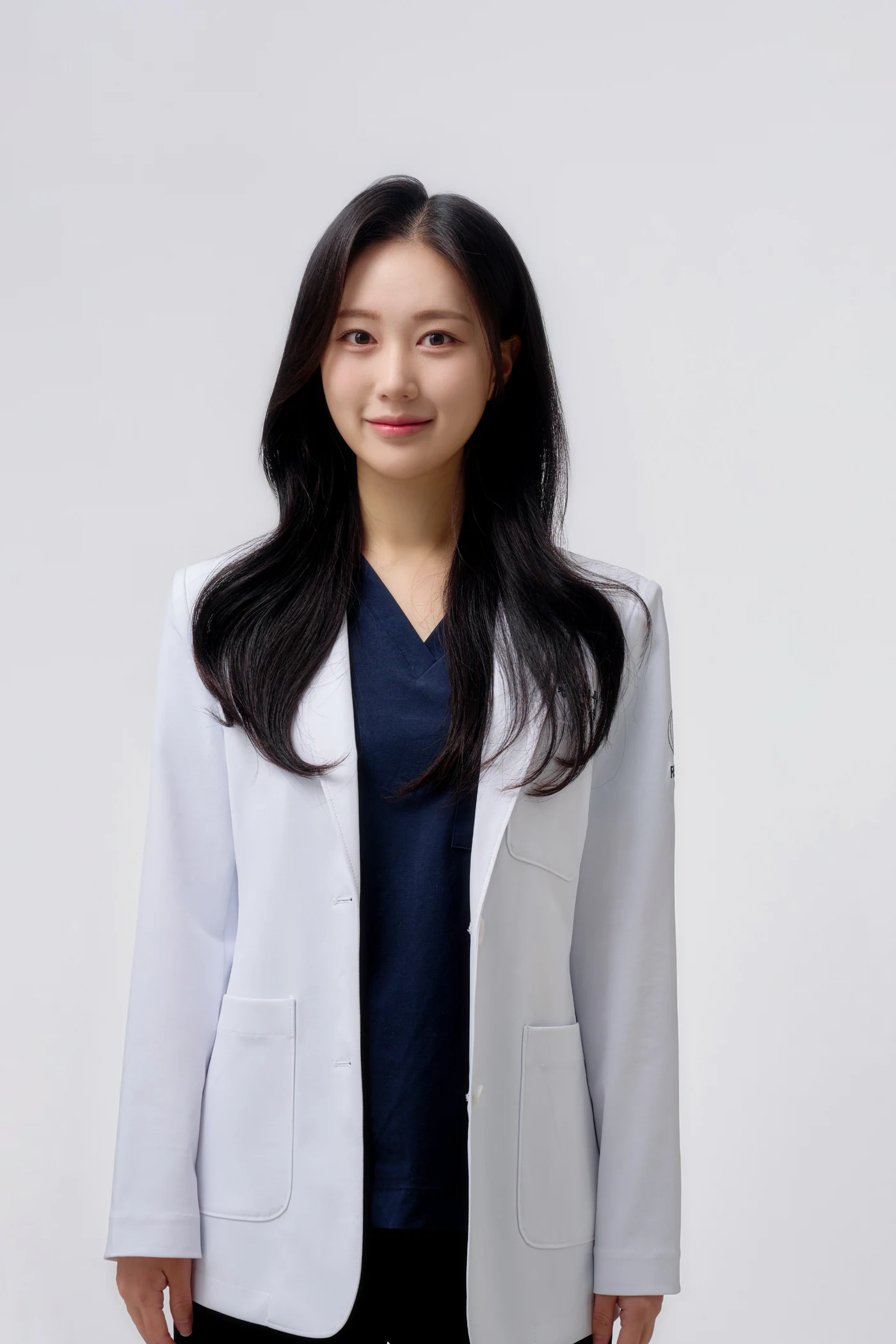 Dr. Oh Se Won, director of Kind Global Clinic Myeongdong, in a white coat over navy scrubs, against a light gray studio background.